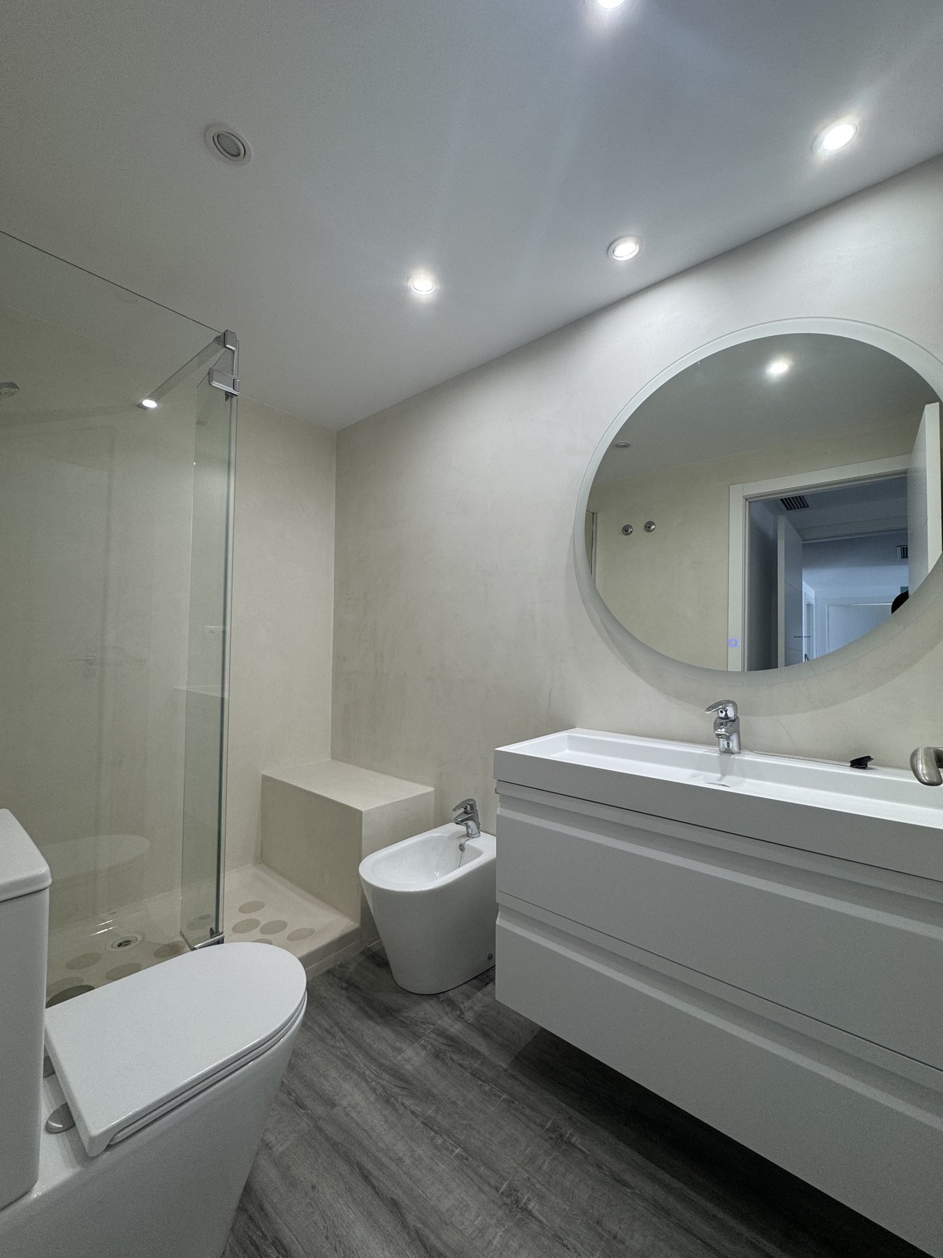 Baño moderno en microcemento beige continuo en Dénia