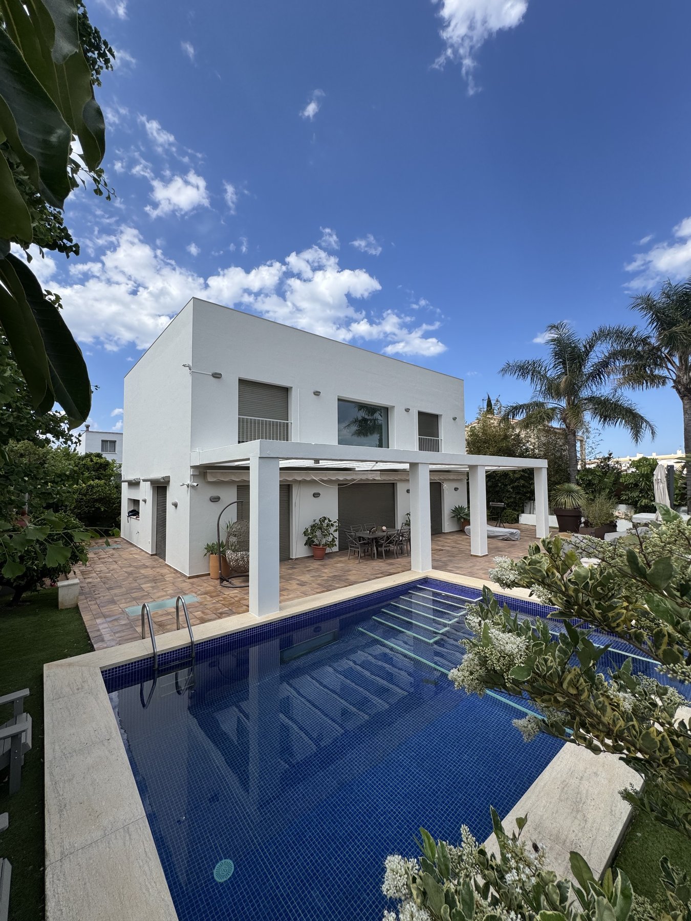 Pintura exterior de villa moderna con piscina de gresite azul en Pego