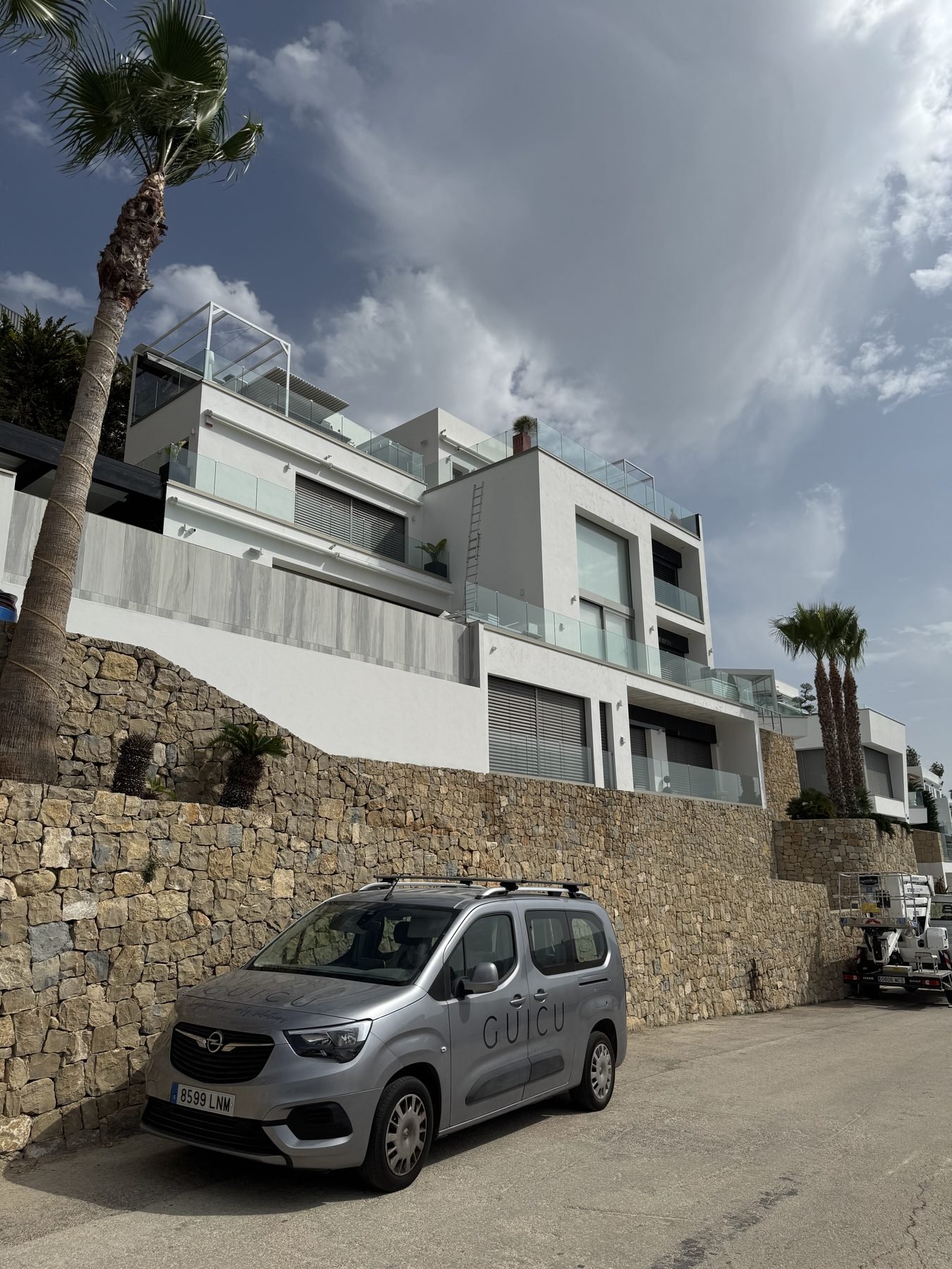 Villa moderna recién pintada de blanco con muro de piedra y furgoneta de GUICU en Moraira