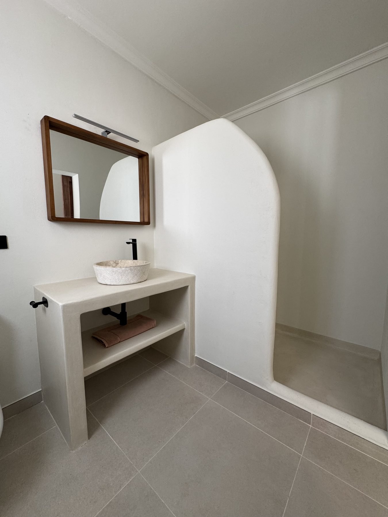 Baño en microcemento con ducha en arco y mueble lavabo de obra en Casa Gafarro, Jávea